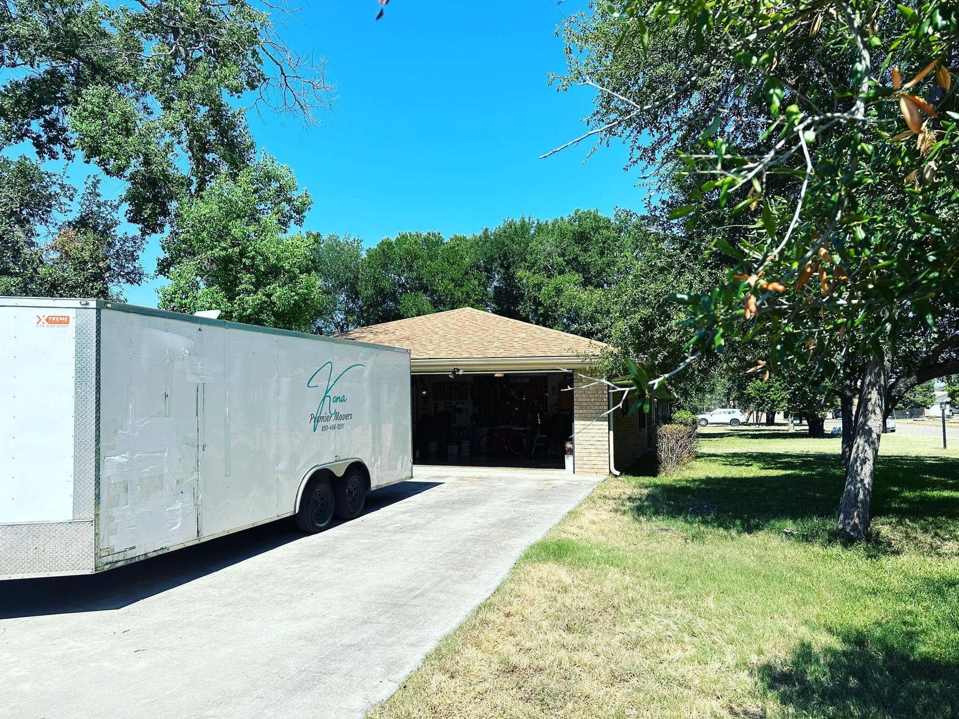 A white trailer is parked in front of a house.