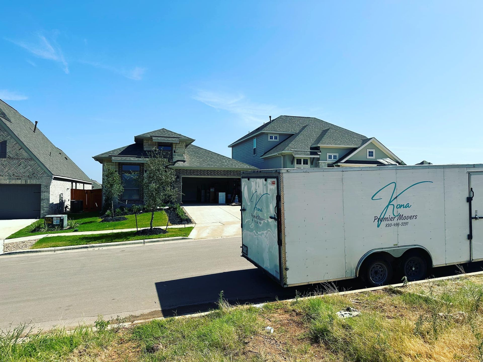A white trailer is parked in front of a large house.
