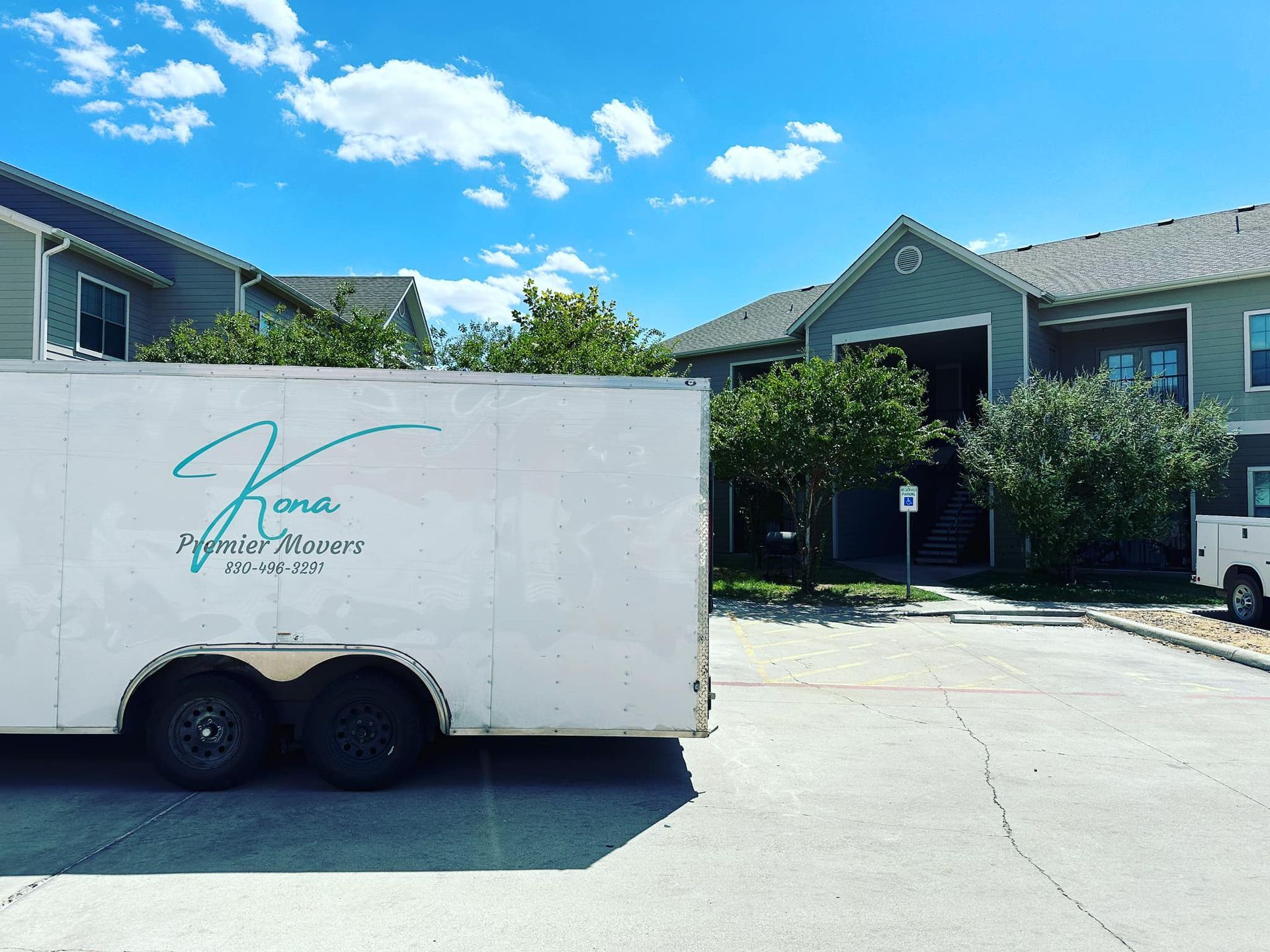 A white trailer is parked in front of a building.