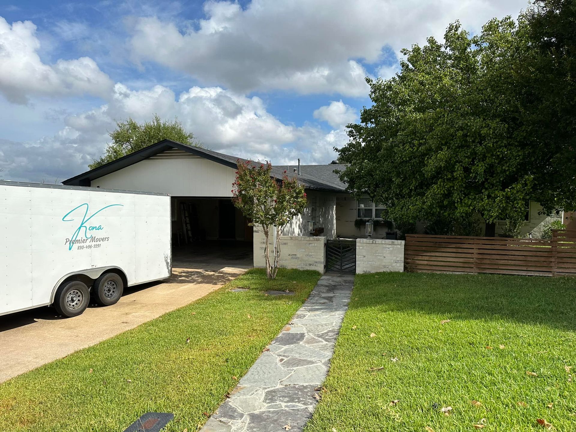 A white trailer is parked in front of a house.