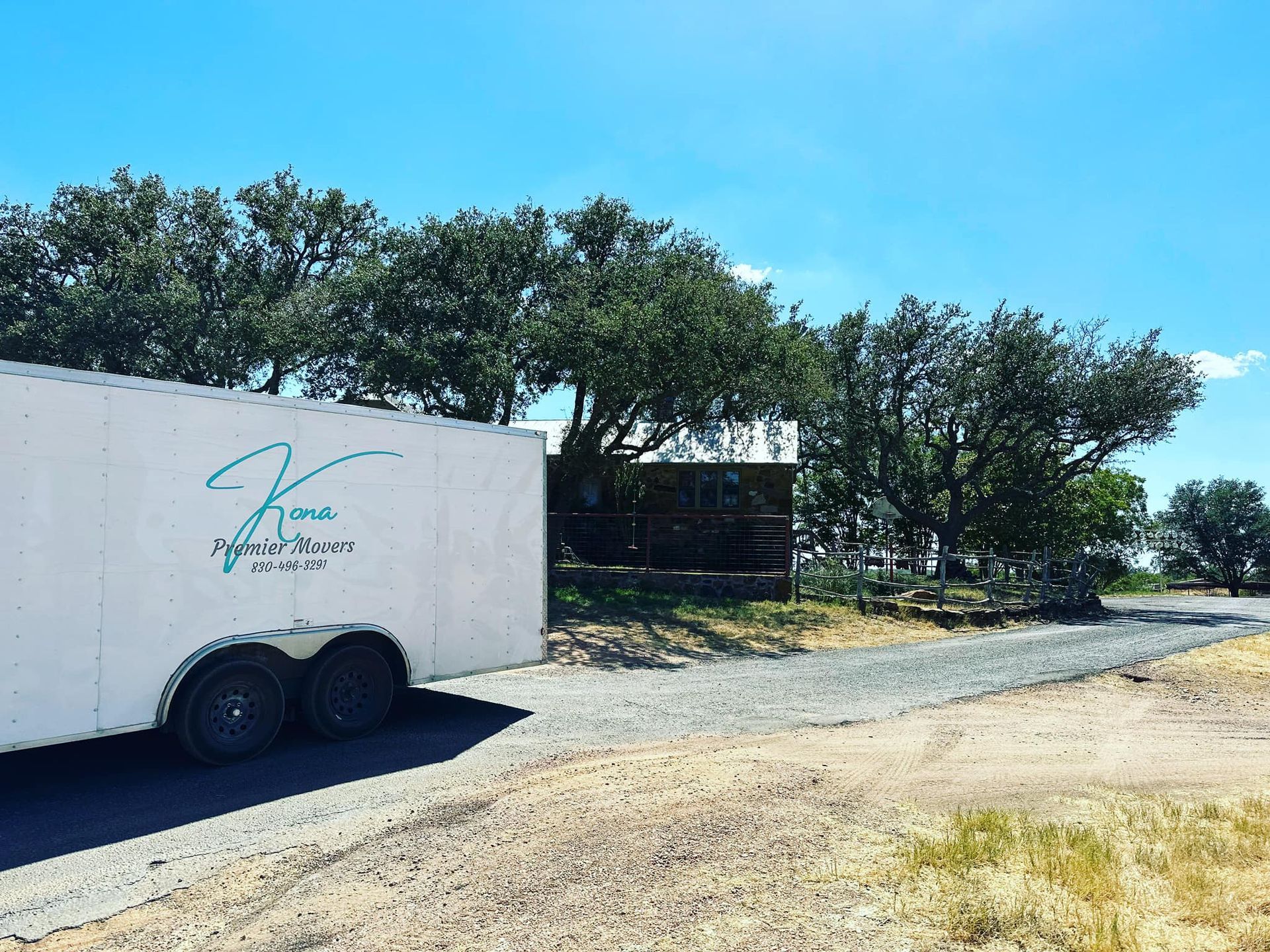 A white trailer is parked on the side of a dirt road.