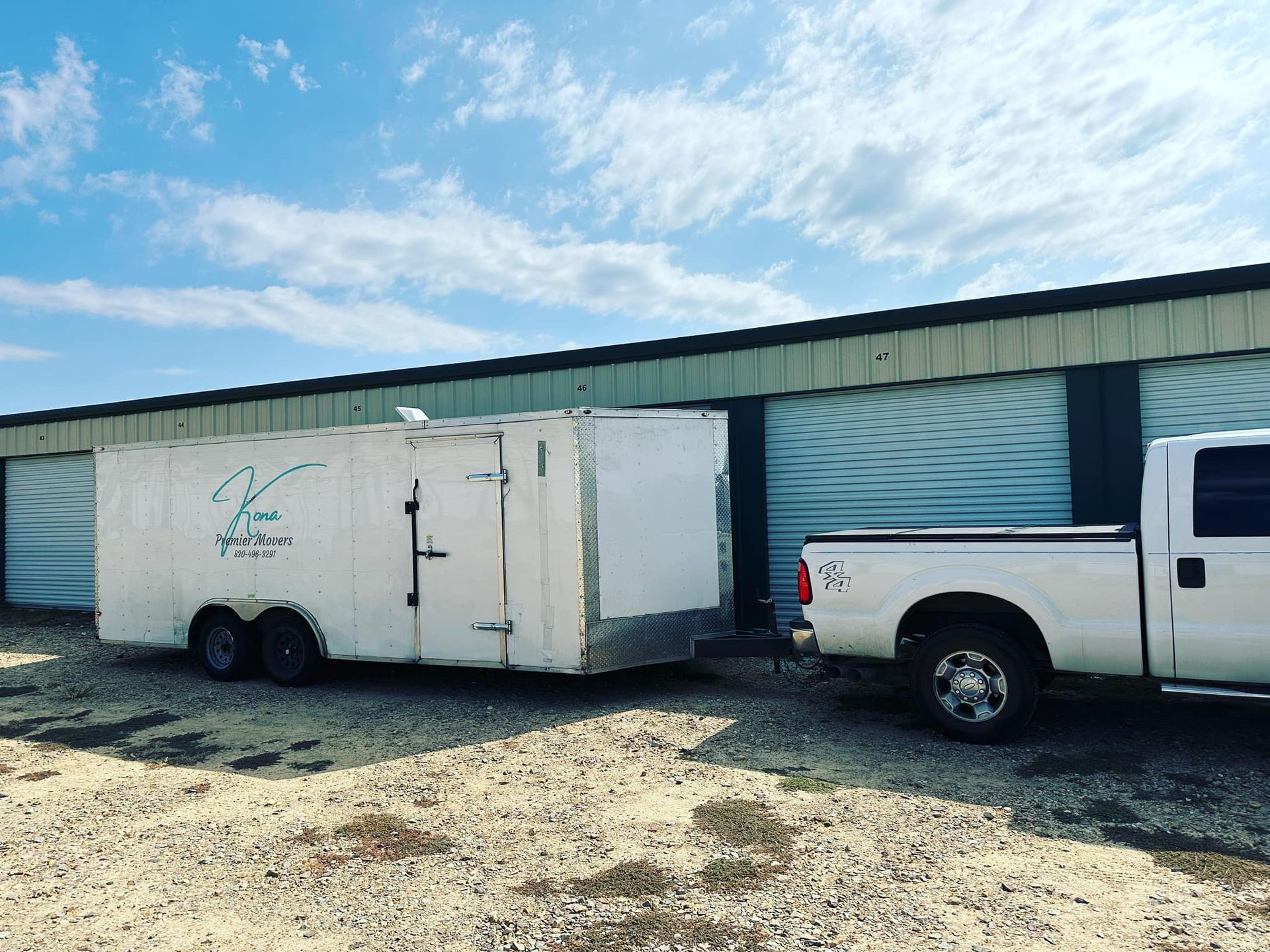 A white truck with a trailer attached to it is parked in front of a building.