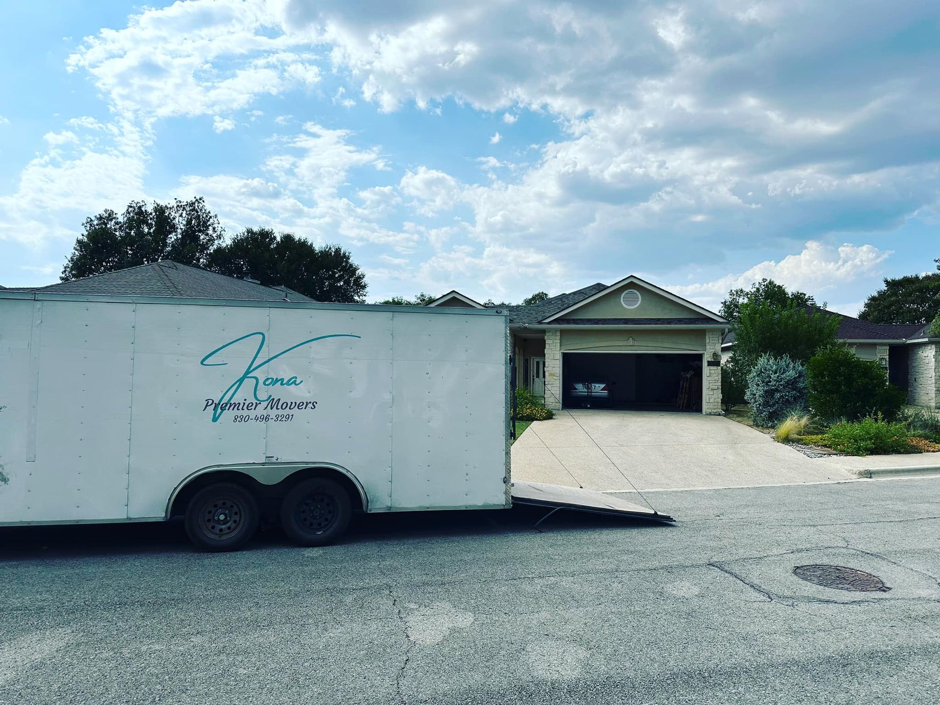 A white trailer is parked in front of a house.