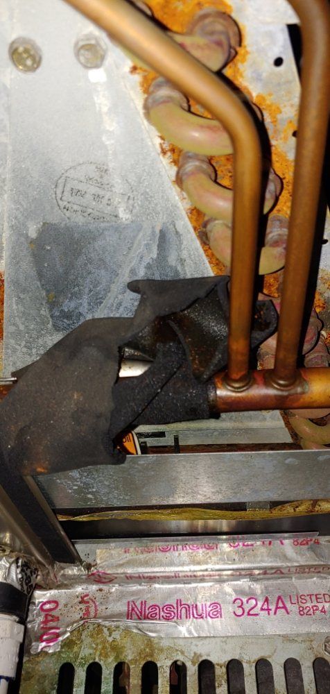 A close up of a person welding copper pipes on a machine.