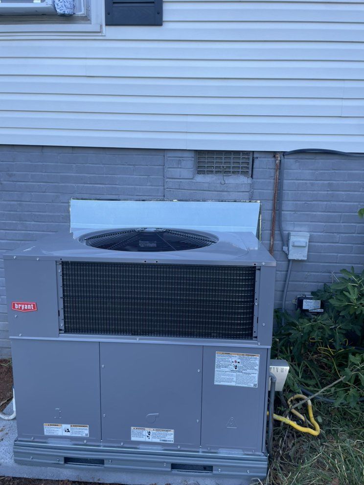 A large air conditioner is sitting on the side of a house.