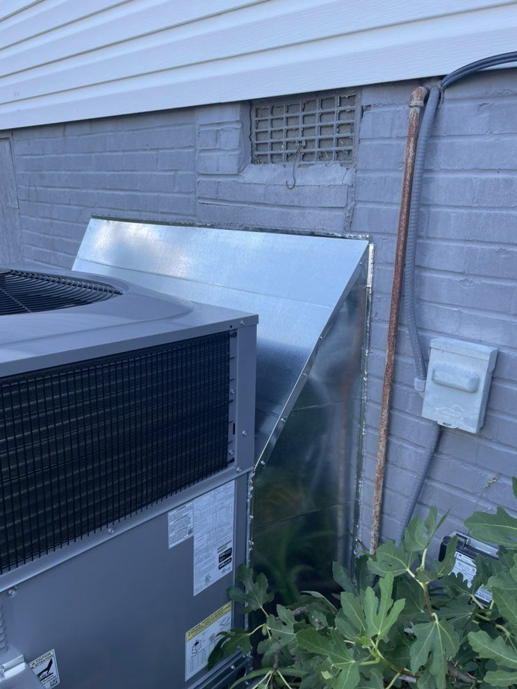 A large air conditioner is sitting on the side of a brick building.