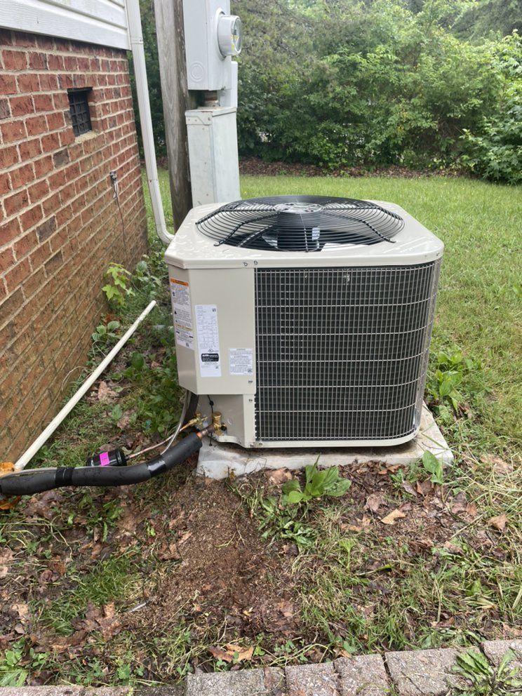 A large air conditioner is sitting on the side of a brick building.