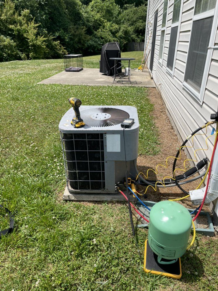An air conditioner is being installed in the backyard of a house.