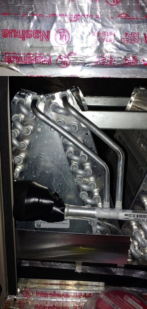 A close up of a refrigerator with a lot of pipes coming out of it.