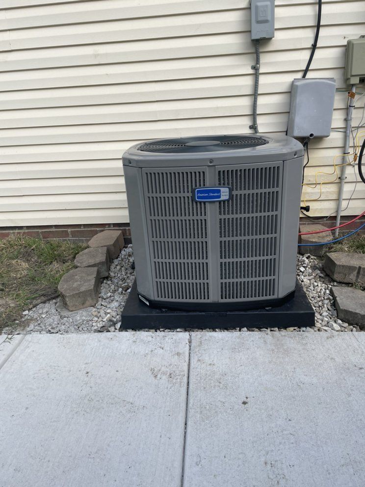 An air conditioner is sitting on the side of a house.