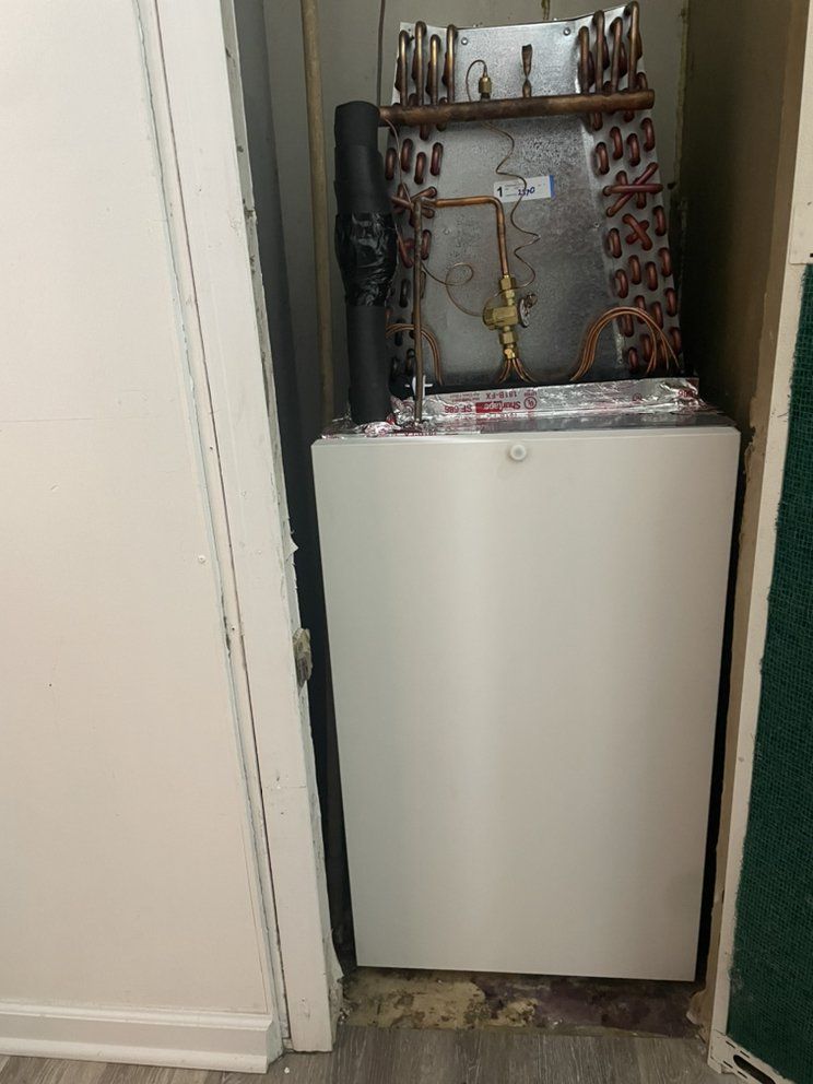 A refrigerator is sitting in a closet next to a door.