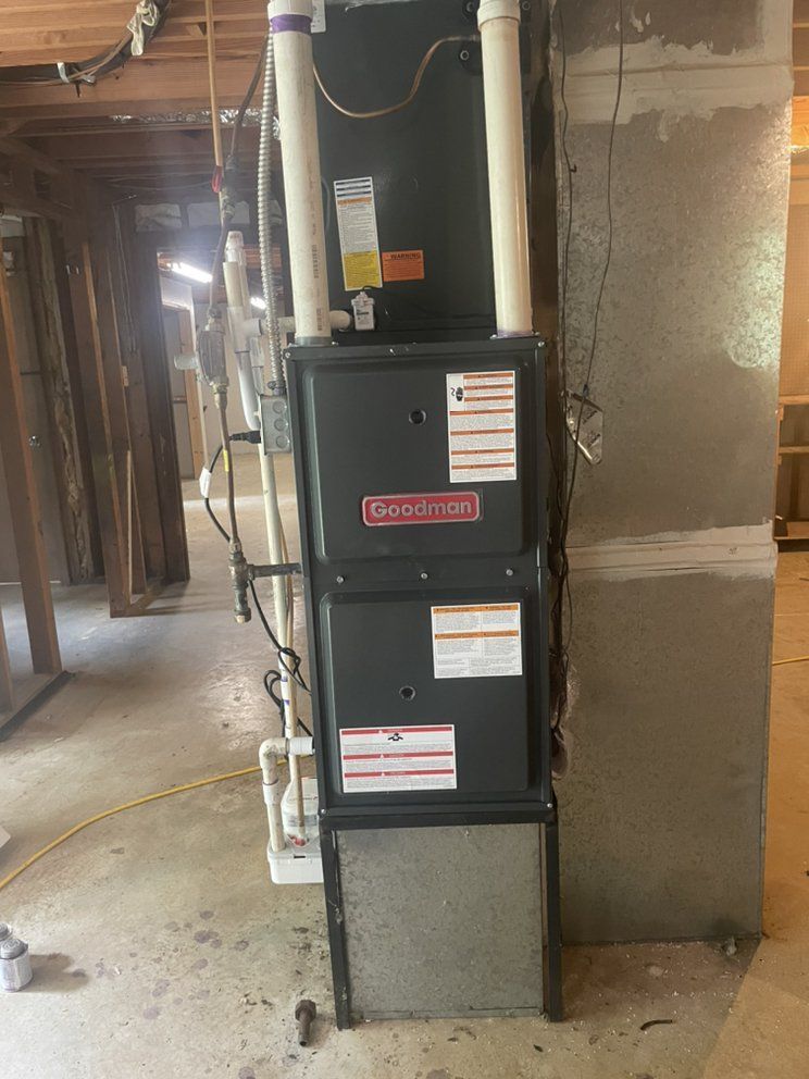 A gas furnace is sitting in a basement next to a wall.
