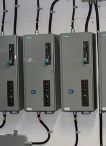 Une rangée de boîtiers électriques est alignée sur un mur