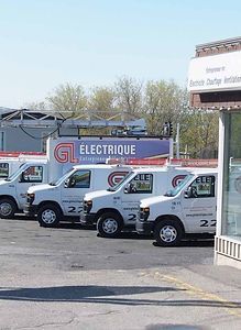 Une rangée de camionnettes blanches est garée devant un bâtiment.