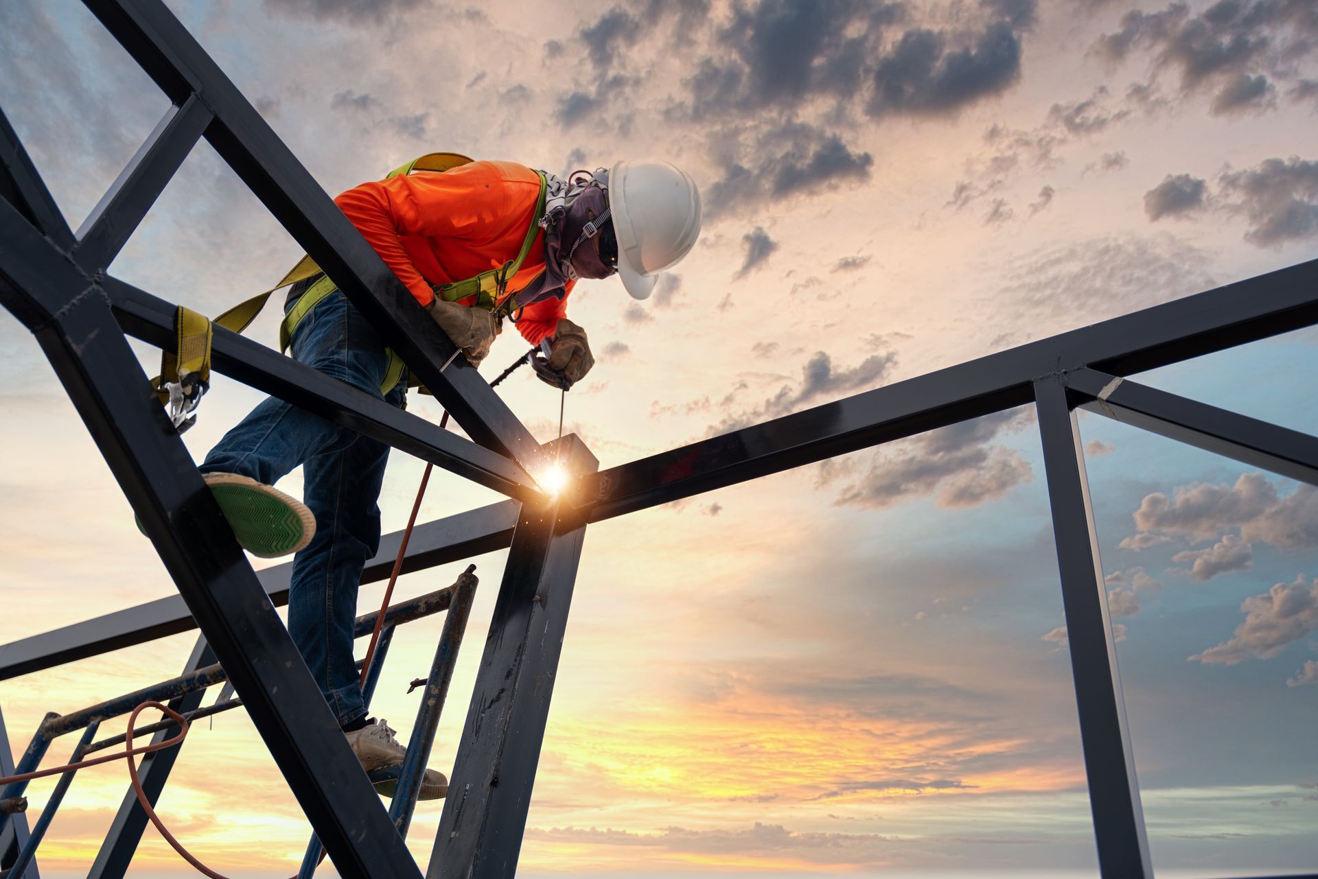 Un ouvrier du bâtiment soude une structure métallique sur le toit d'un bâtiment.
