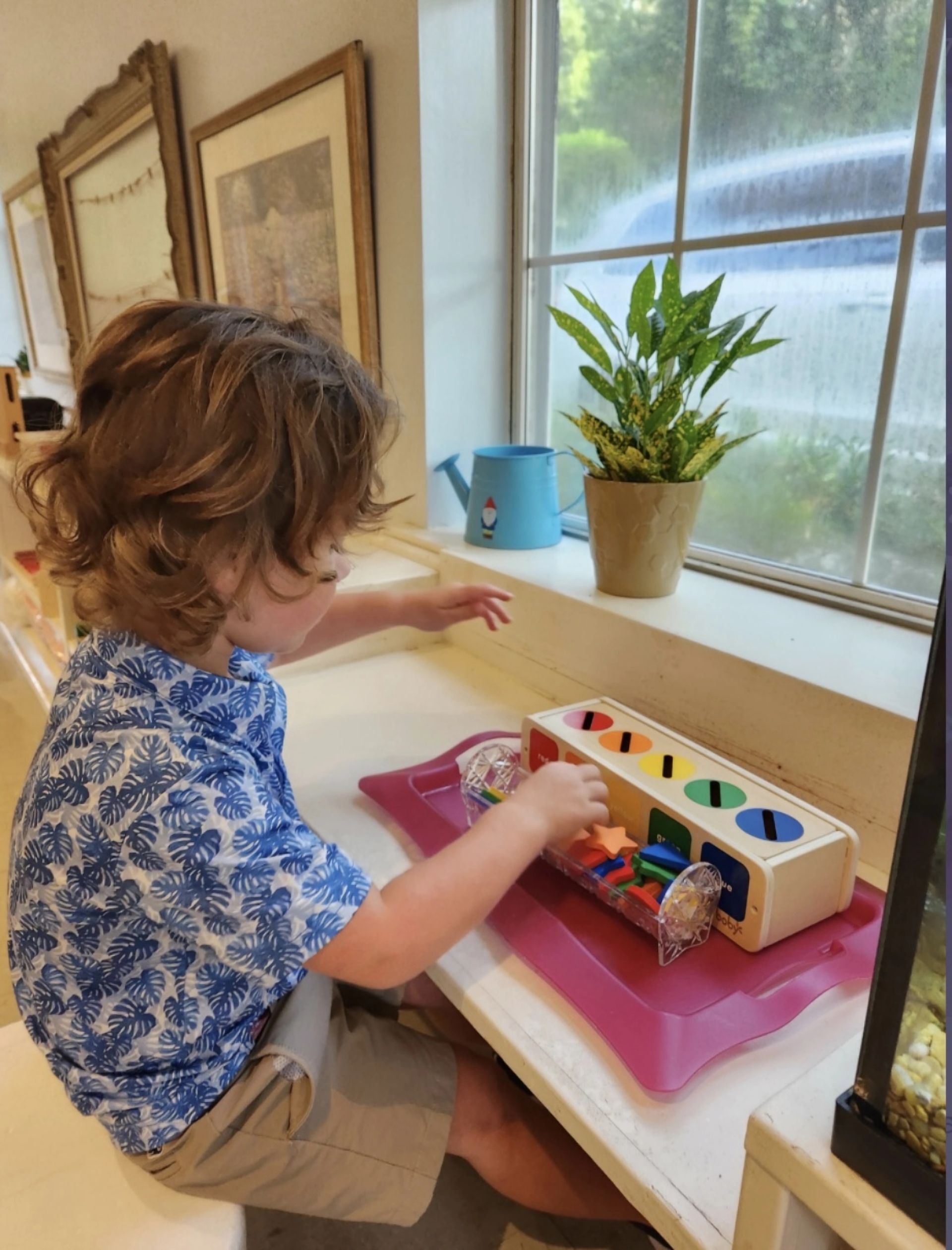 A young boy is playing with a toy in front of a window