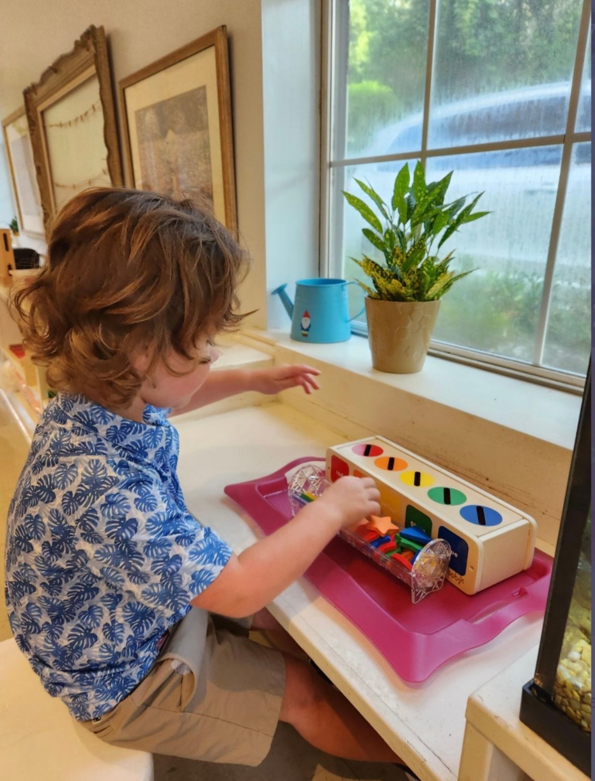 A young girl is playing with a toy in front of a window