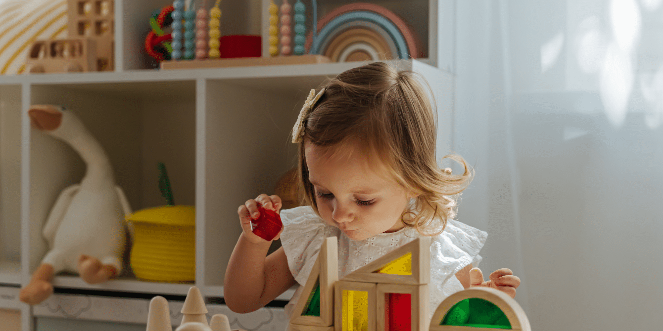 A little girl is playing with wooden blocks in a room.