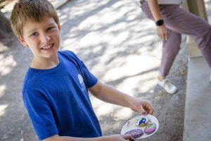 A young boy in a blue shirt is holding a plate of cookies.