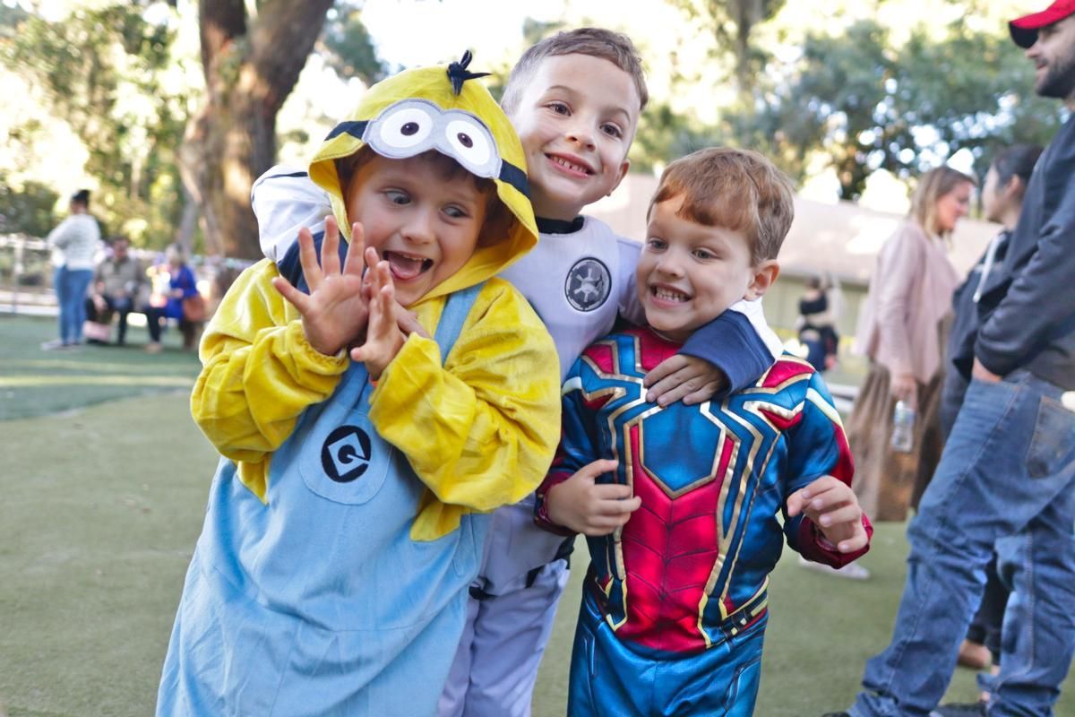 A boy and two girls are laying on the grass in a park.