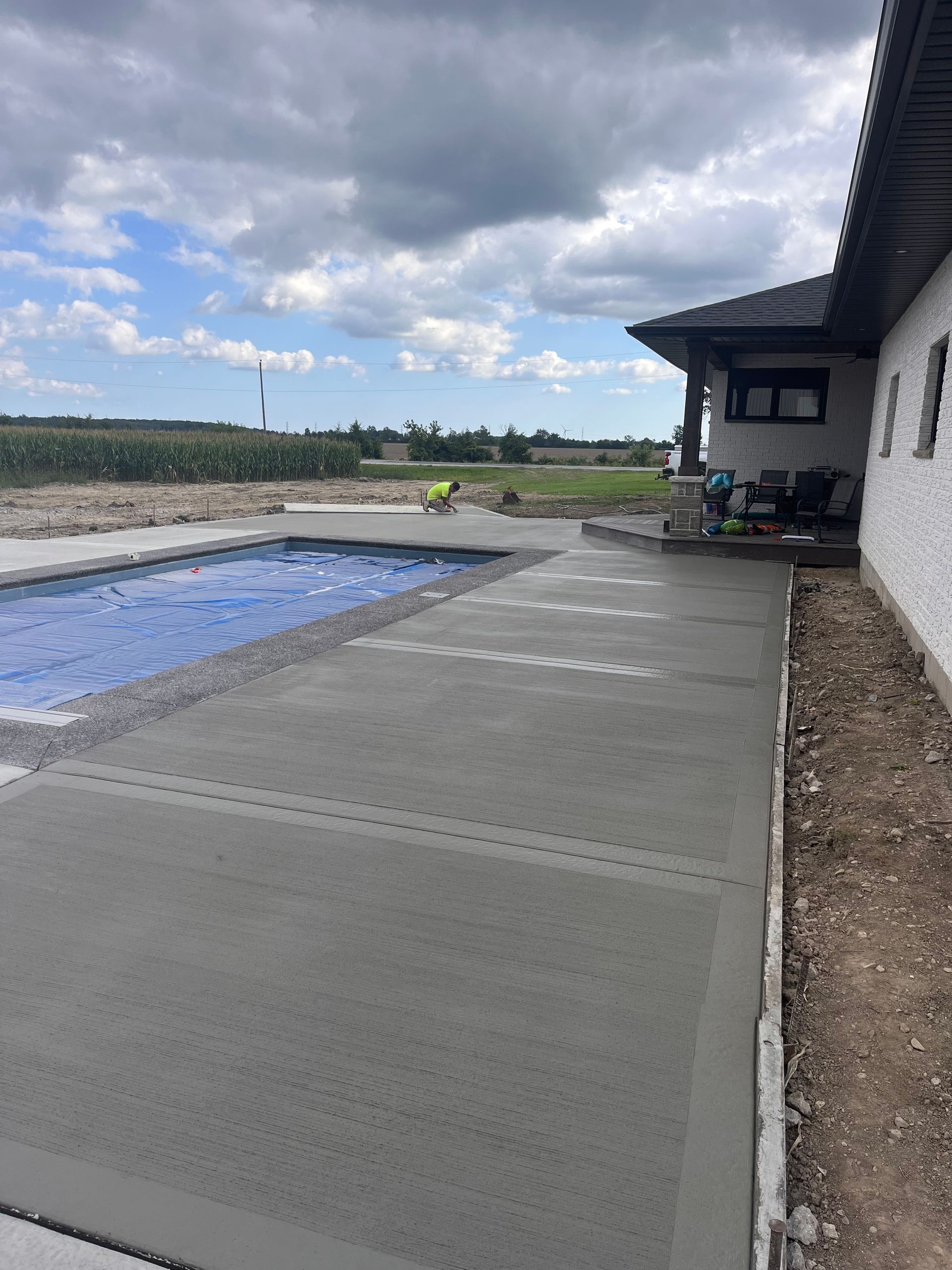 A concrete walkway leading to a swimming pool next to a house.