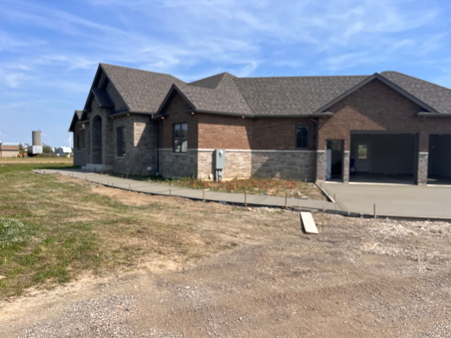 A large brick house with a concrete driveway in front of it