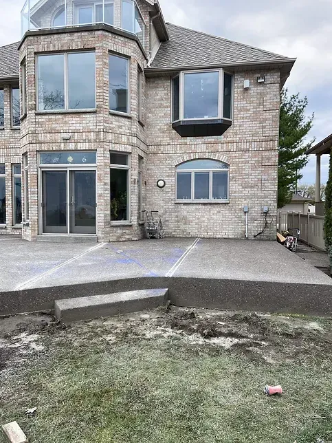 A large brick house with a concrete patio in front of it.
