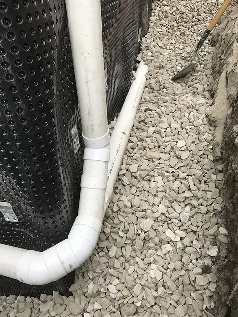 A white pipe is sitting on top of a pile of gravel.