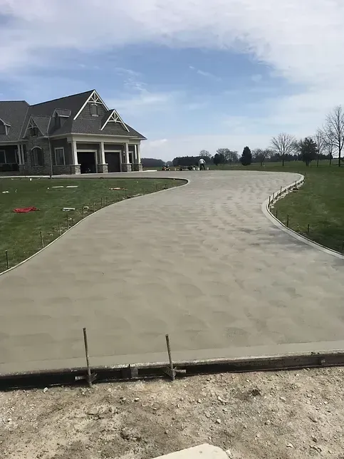 A concrete driveway is being built in front of a large house.