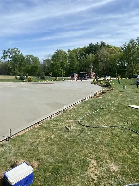 A cooler is sitting on the grass next to a concrete driveway.