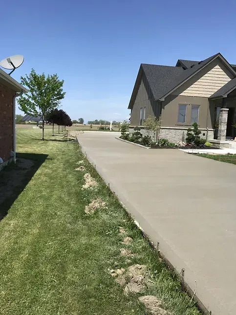 A concrete driveway leading to a house with a satellite dish on top of it.