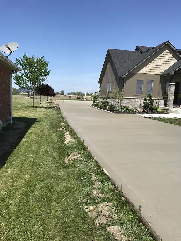 A concrete driveway leading to a house with a satellite dish on the roof.