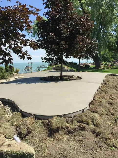 A concrete driveway with a tree in the middle and a view of the ocean.