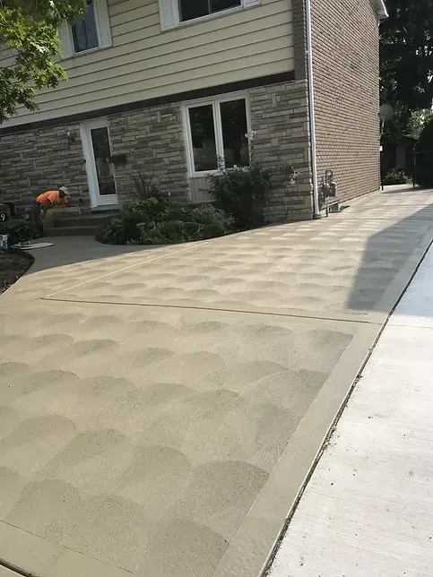 A brick house with a concrete driveway in front of it.