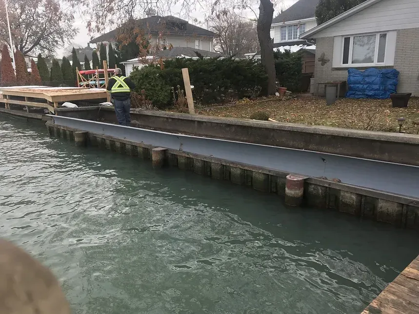 A man is standing on a dock next to a body of water.