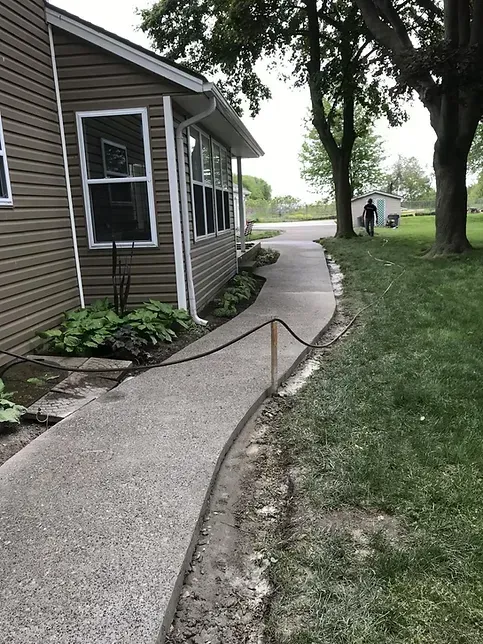 A concrete walkway is being built in front of a house.