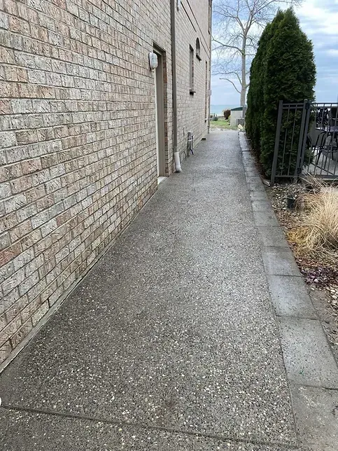 A sidewalk leading to a building with a brick wall.