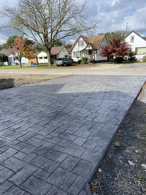 A driveway with a car parked in front of a house in a residential area.