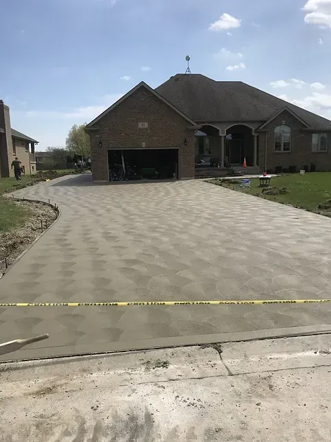 A brick house with a concrete driveway in front of it.
