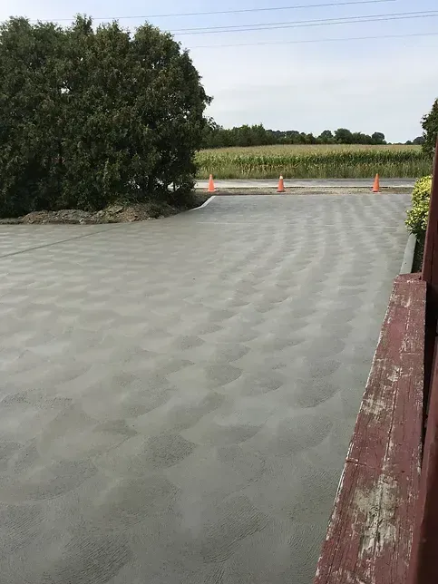 A concrete parking lot with trees and cones in the background.