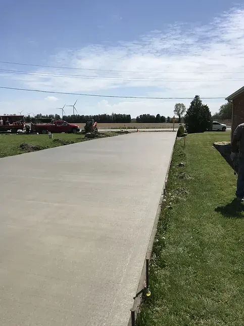 A man is standing on the side of a concrete driveway.