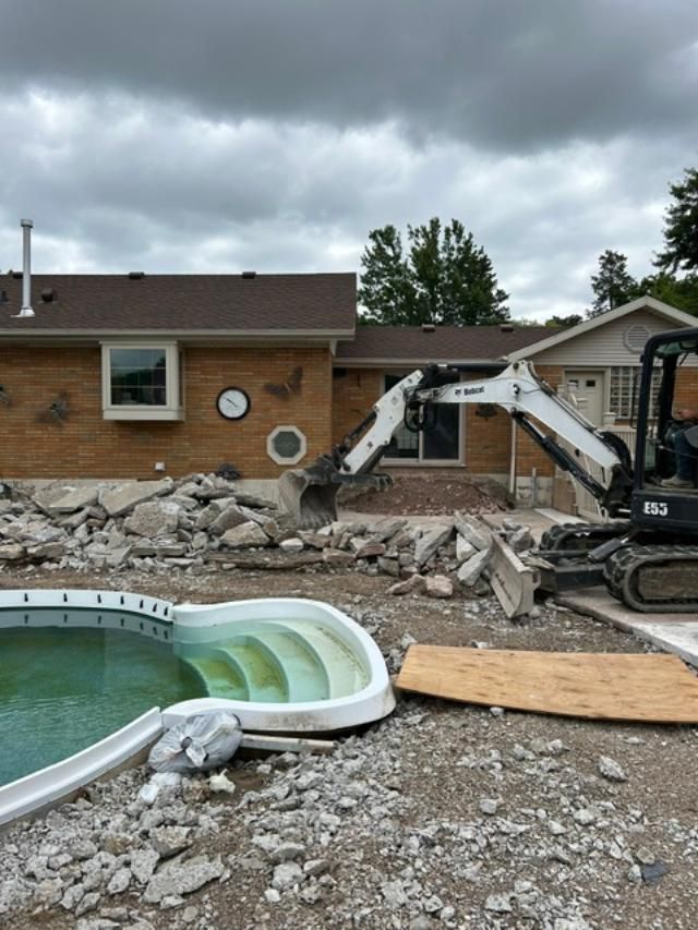 A swimming pool is being demolished in front of a house.