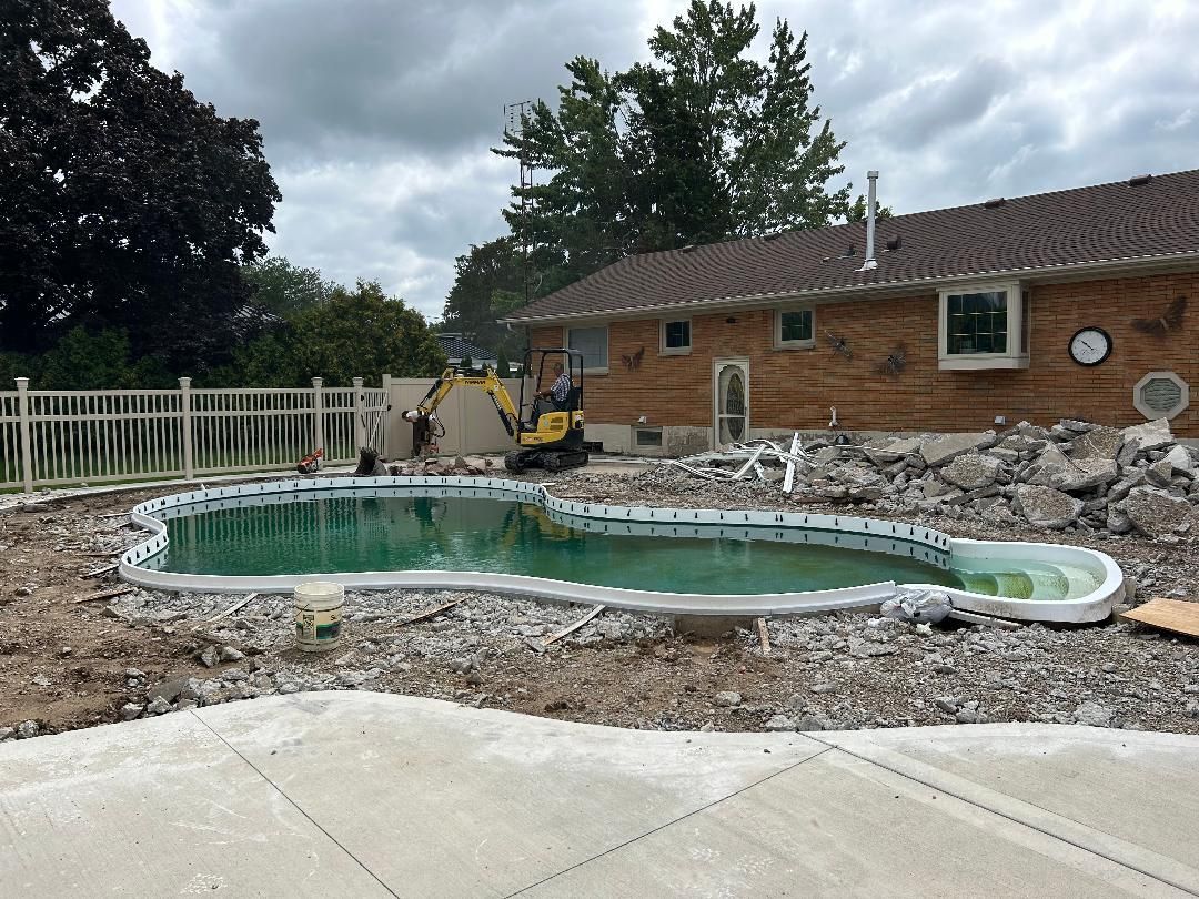 A swimming pool is being demolished in front of a house.