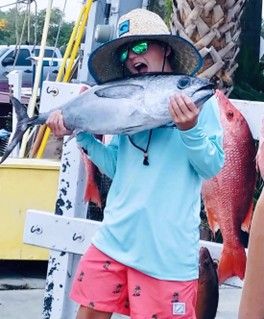 A young person is holding a large fish after a fishing charter with Reel Groovy Experiences.