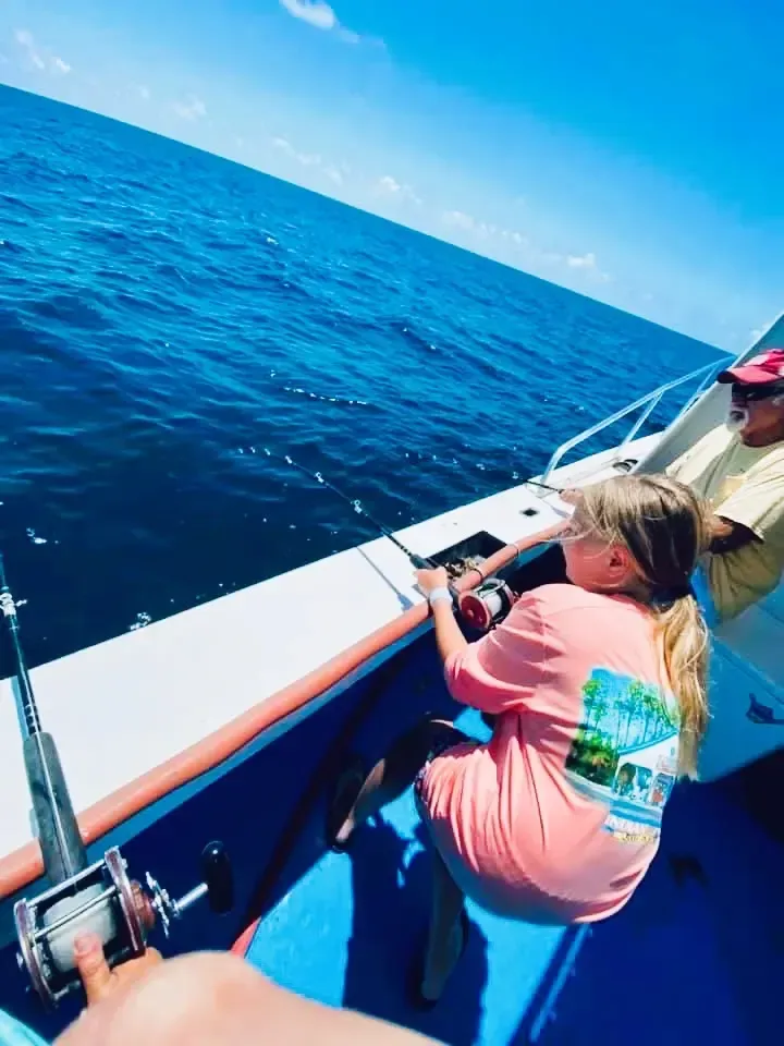 A young girl fishing a strong fish on her deep sea fishing charter with Reel Groovy Experiences in Panama City Beach, FL.