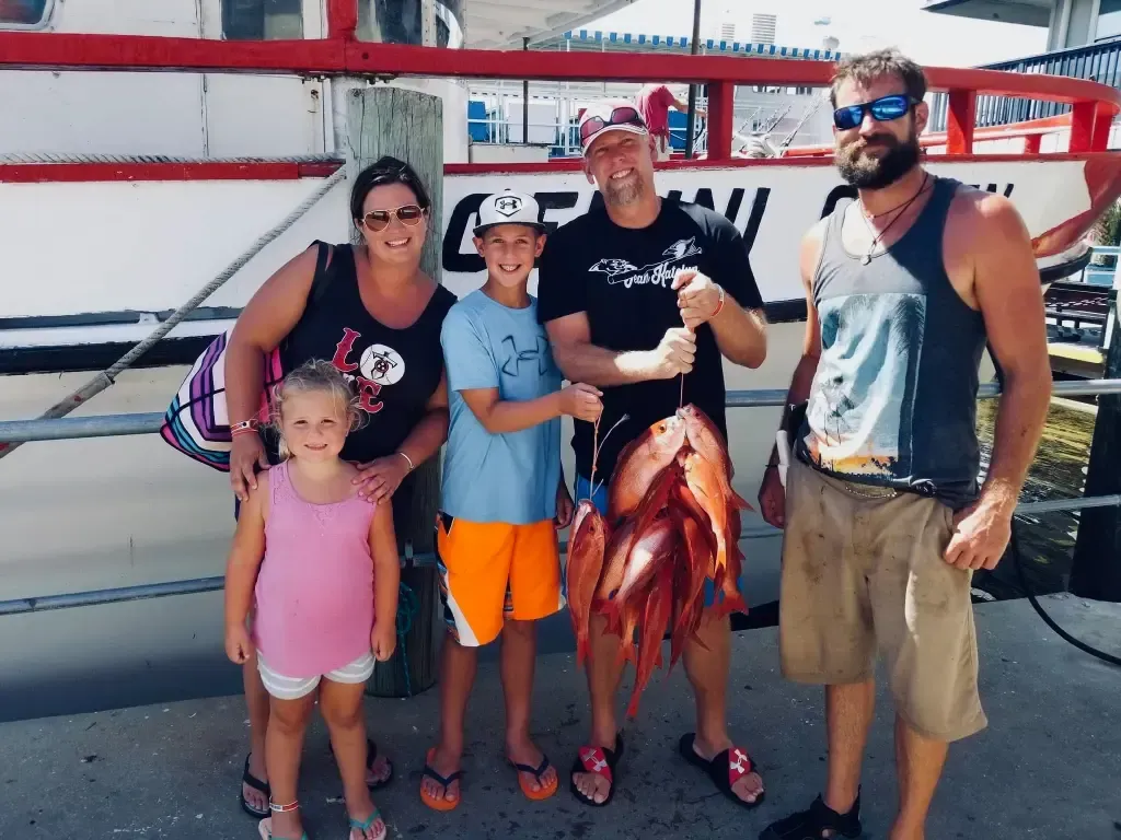 A family posing for a picture with Captain Gary after their fishing charter.