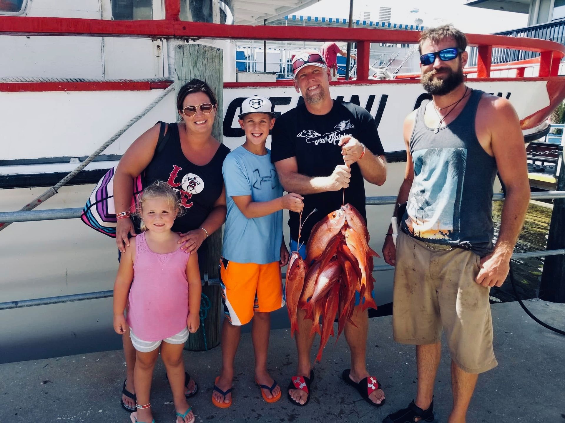 A family posing for a picture with Captain Gary after their fishing charter.
