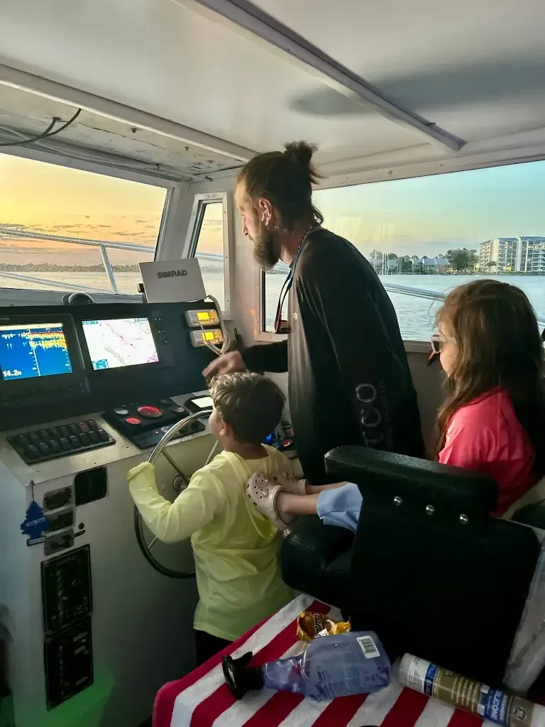 Family-friendly sunset cruise Panama City Beach – Captain Gary showing kids the helm