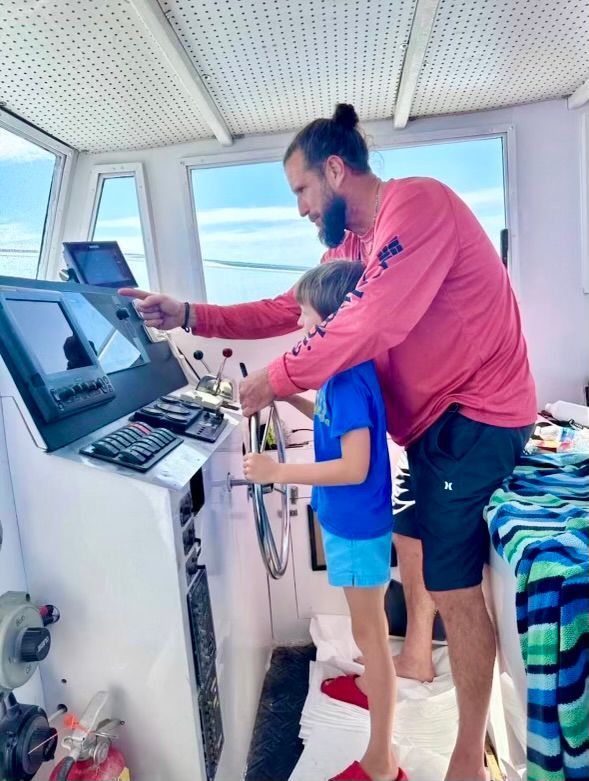 Family-friendly fishing charter Panama City Beach – Captain Gary showing child the helm