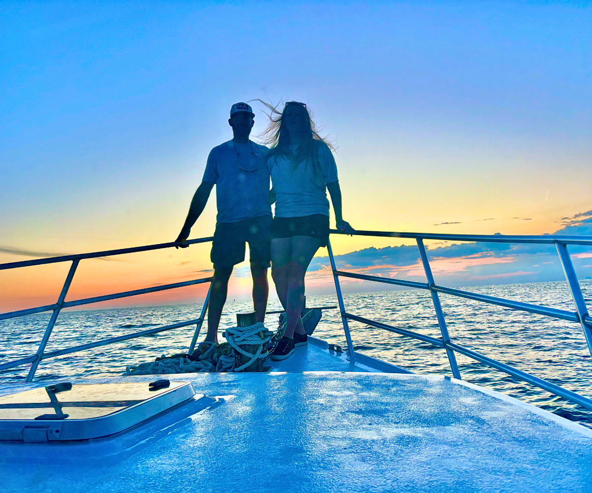 A couple is posing for a picture while on a sunset cruise with Reel Groovy Experiences.